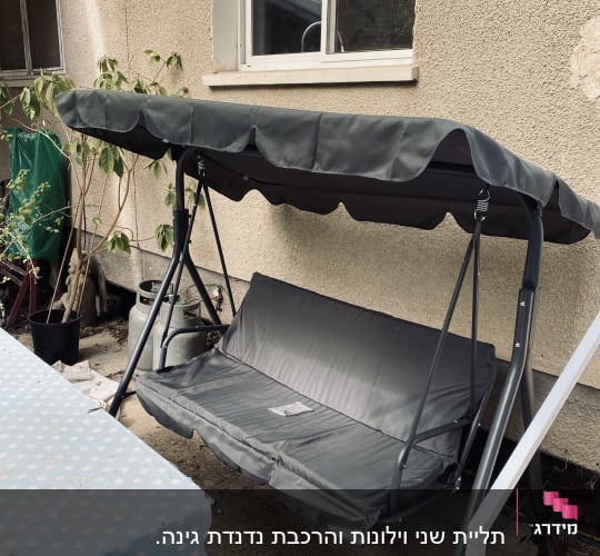 נדנדה חיצונית עם גג ליד שולחן מכוסה מפה מנוקדת